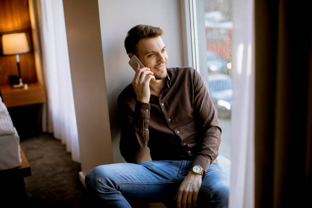 istock Young man using mobile phone in the room by window 1134435368