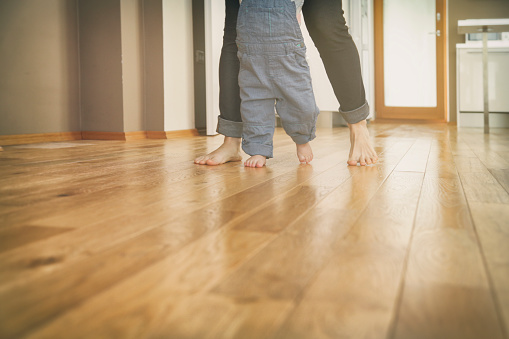 First steps of a child with his mother's help. Both barefoot on hardwood floor. What a joy.....