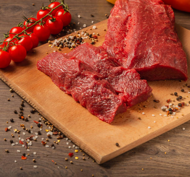 istock Raw beef on a wooden background with spices and vegetables 1134437310