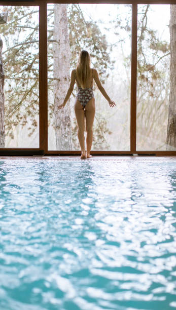 istock Young woman standing by pool in the spa 1134437325