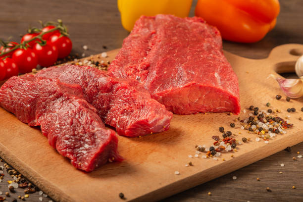istock Raw beef on a wooden background with spices and vegetables 1134439248