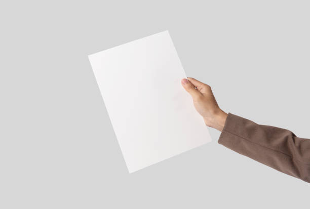 istock hand showing blank paper A4 flyer for mockup template logo branding on grey background. 1134440072