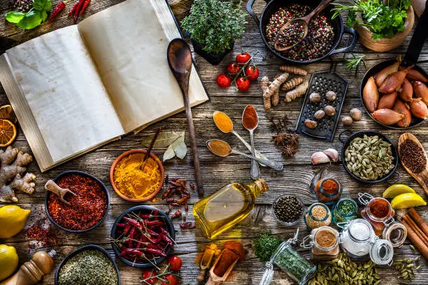 Photo of Cooking concepts: Cookbook with spices and herbs shot from above on rustic wooden table