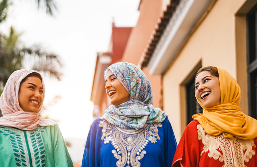 Happy Muslim women walking in the city center - Arabian young girls having fun spending time and laughing together outdoor - concept of people, culture and religion