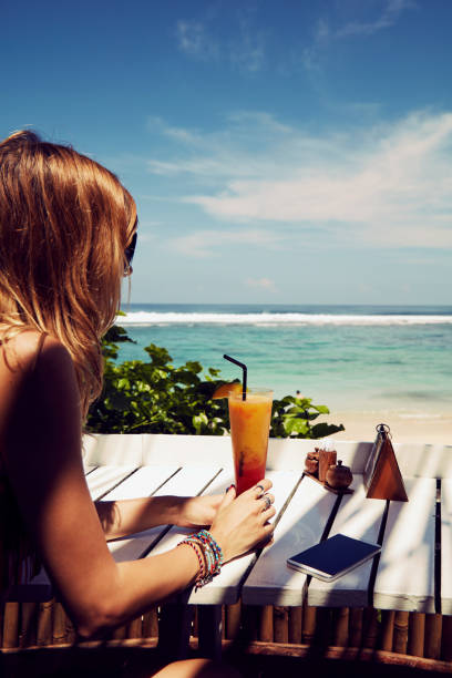 istock Beautiful woman drinking cocktail and using cellphone on the tropical sandy beach. 1134449166