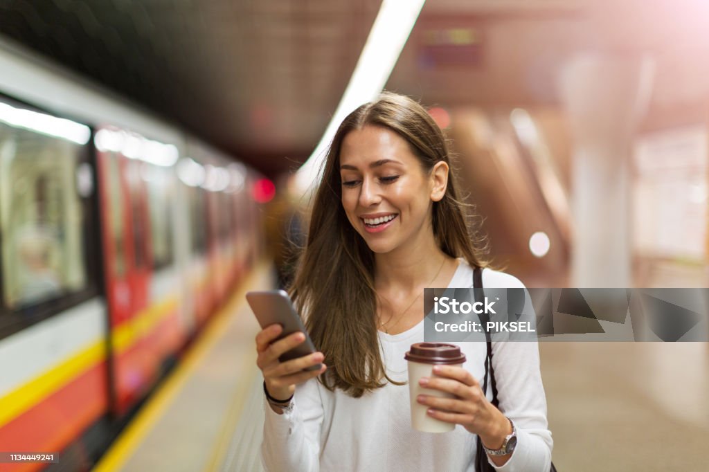 Young woman at subway station Woman using mobile phone at subway station Women Stock Photo