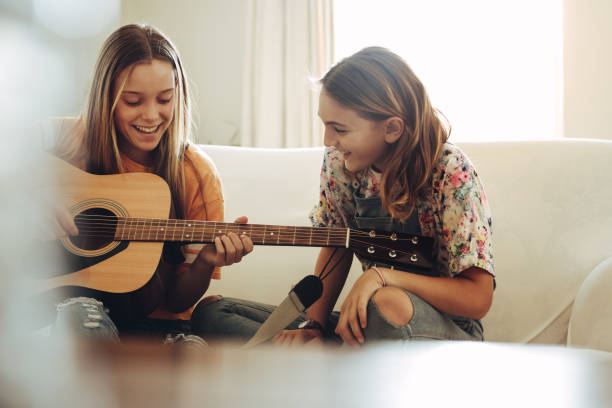 istock Happy girls playing guitar at home 1134449867