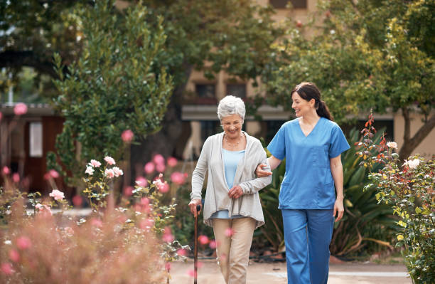 She knows just how to make each patient feel special Shot of a caregiver and her patient out for a walk in the garden assisted living stock pictures, royalty-free photos & images