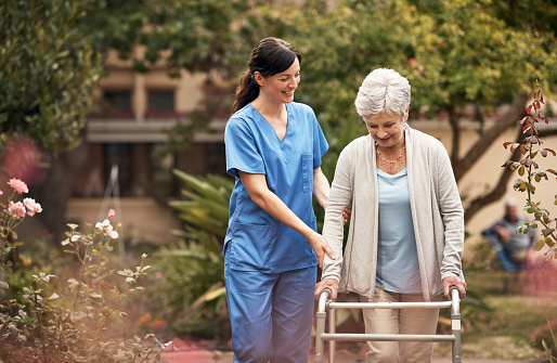 Shot of a senior woman with her walker out for a stroll in the garden with her caregiver
