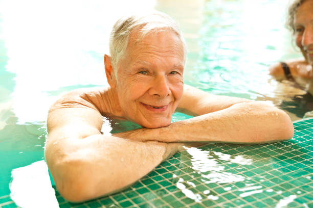 istock Smiling senior man by woman leaning at poolside 1134456241