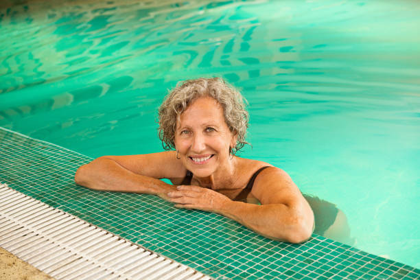istock Smiling retired senior woman leaning at poolside 1134456702