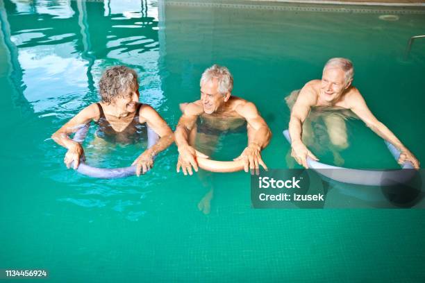 Males And Female Swimming With Noodle Floats Stock Photo - Download Image Now - Senior Adult, Senior Men, Water