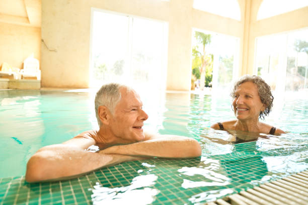 istock Smiling senior male and female leaning at poolside 1134457762
