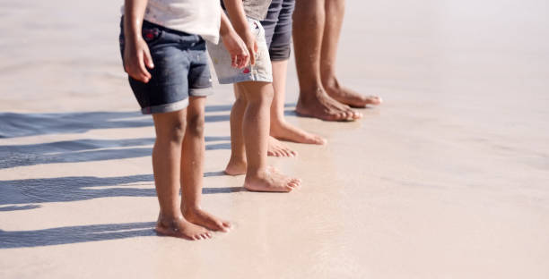Three pairs of feet on the sand. Family on vacations. Feet and the grains of sand.
