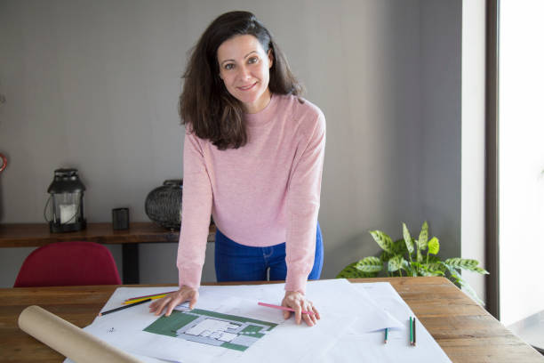 istock Cheerful lady designer working with blueprint in cozy office 1134459599