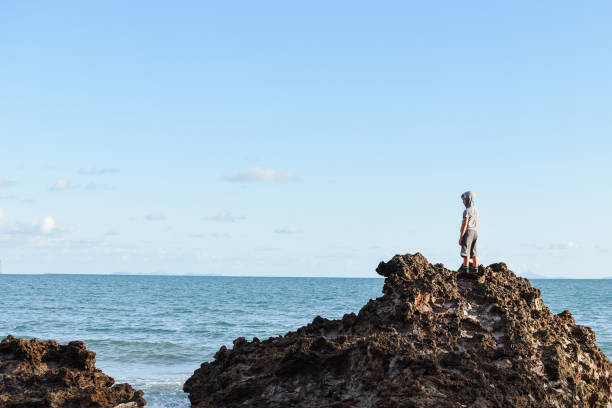 istock Person standing on isolated rocks overlooking the ocean 1134461776