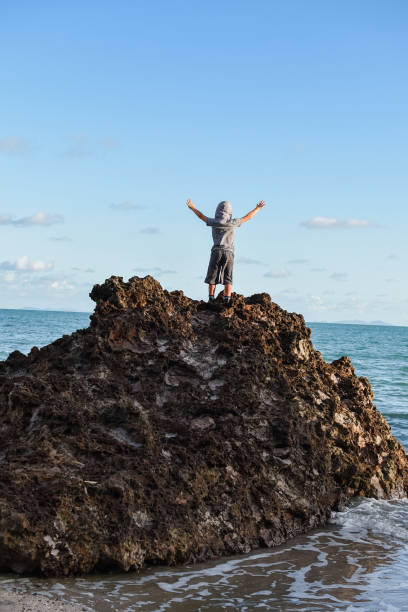 istock Person standing on isolated rocks overlooking the ocean 1134461813