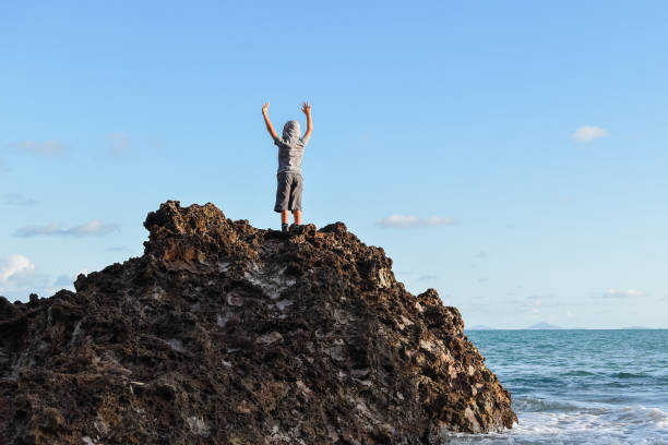 istock Person standing on isolated rocks overlooking the ocean 1134461863