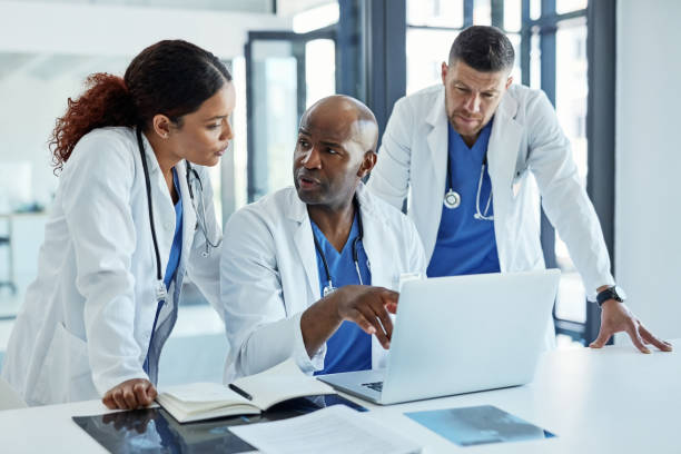 We should research more about this infection Shot of a group of medical practitioners working on a laptop together researcher and doctor stock pictures, royalty-free photos & images