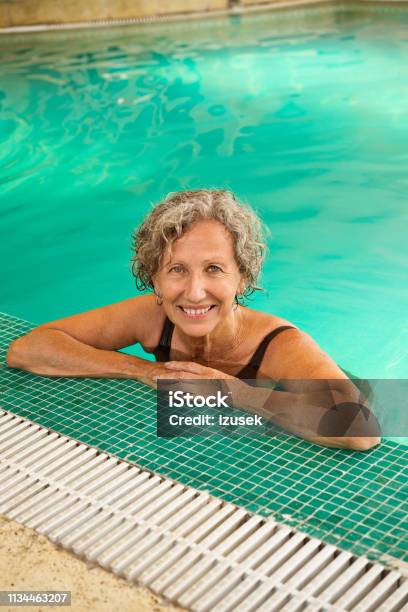Smiling Retired Senior Female Leaning At Poolside Stock Photo - Download Image Now - Senior Adult, Swimming Pool, 60-64 Years