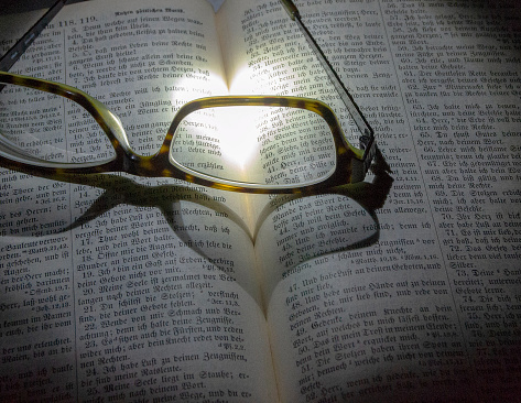 German bible opened with glasses lying on it with two images of love
