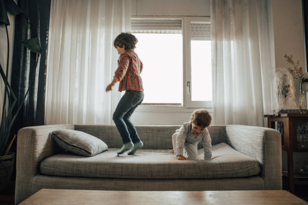 ソファーでジャンプする兄弟 - domestic life jumping child sofa ストックフォトと画像