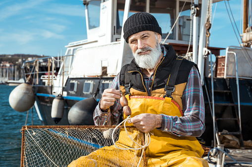 Portrait of senior fisherman in front of sea