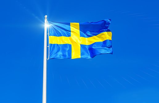 National flag of Sweden flying in the wind against the blue sky
