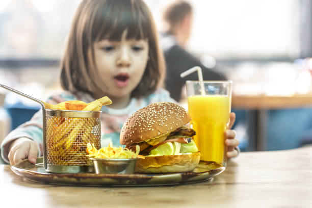 istock Little girl eats in a fast food cafe 1134468760