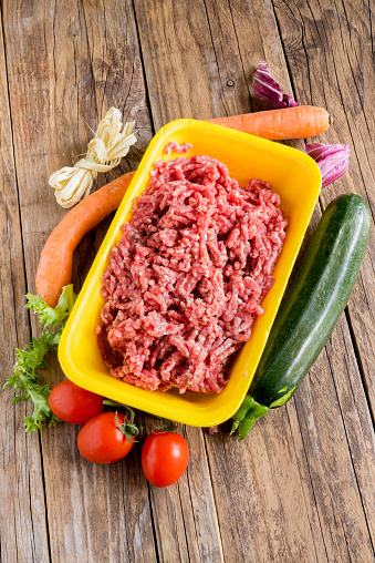 minced meat in polystyrene pan on wooden table