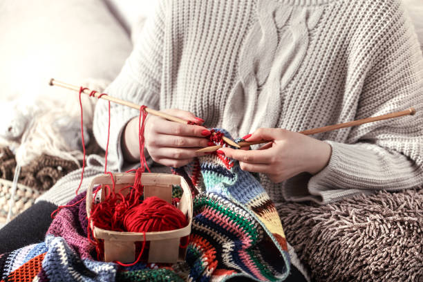 istock woman knits knitting needles on the couch 1134469159