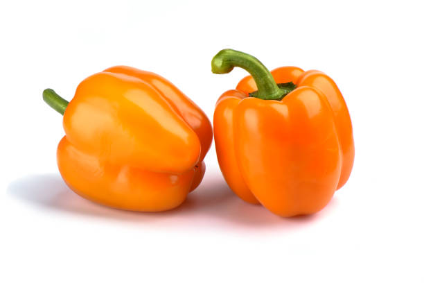 istock Two orange bell peppers isolated on white background 1134469858