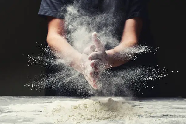 Photo of Clap hands of baker with flour in kitchen