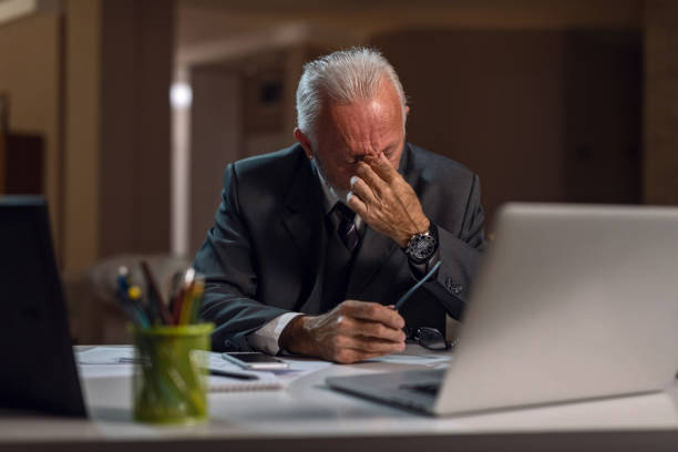 istock Tired senior businessman having headache while working on laptop in the office. 1134470494