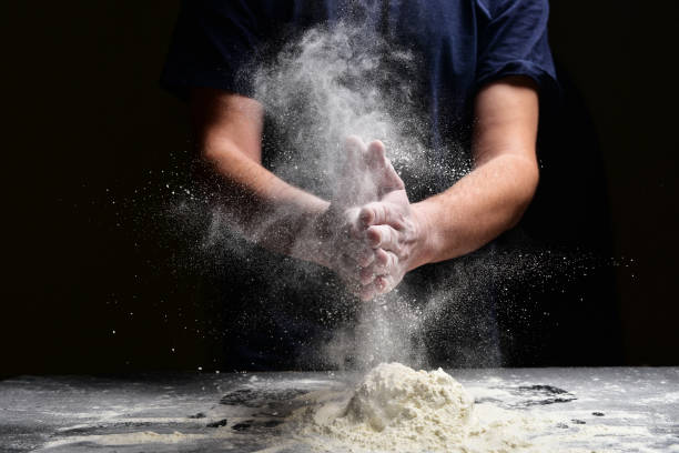 clap de main de chef avec la farine d'éclaboussure - bread making photos et images de collection