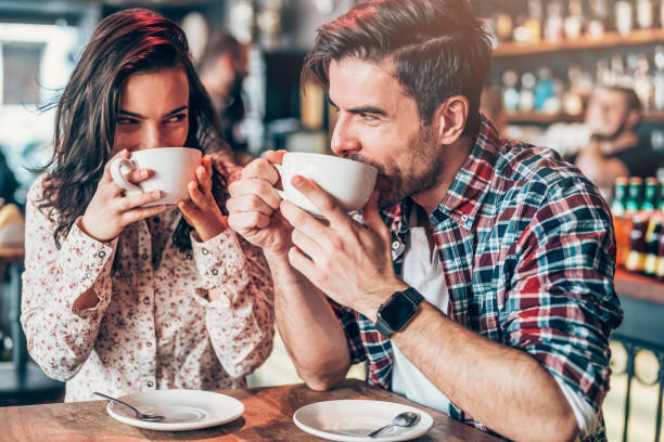 Couple relaxing in a cafe Beautiful young couple drinking coffee and looking each other Romance stock pictures, royalty-free photos & images