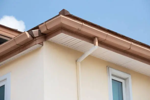 brown steel rain gutter  with blue sky. concept : repair roof in summer before rainy season.