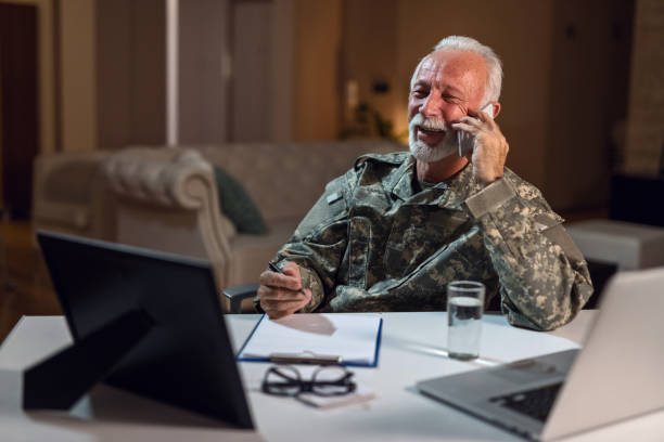 istock Happy mature soldier talking on the phone while doing paperwork in the office. 1134478482