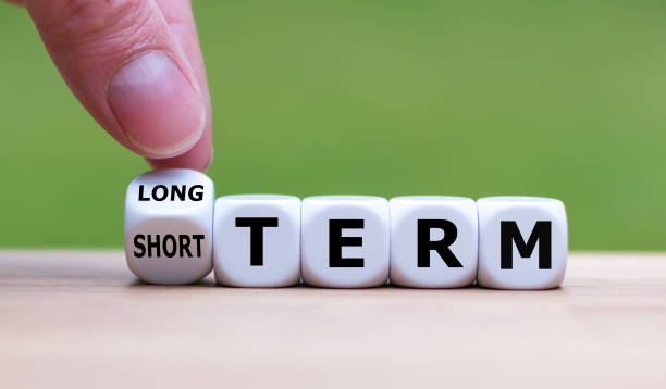 ręka obraca kostkę i zmienia wyrażenie "short term" na "long term" (lub odwrotnie). - short game zdjęcia i obrazy z banku zdjęć
