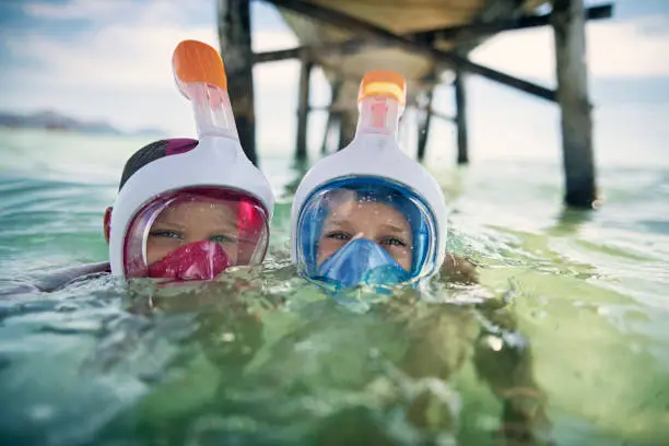 Happy little boys snorkeling in the sea. The boys are wearing a modern full-face snorkel masks. Sunny summer day.
Nikon D850
