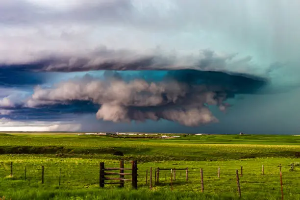 Supercell thunderstorm with dramatic clouds over a green grass field in eastern Montana.