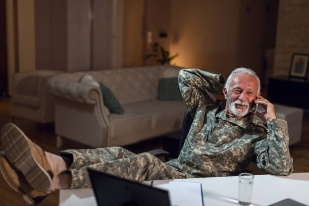 istock Happy mature soldier using mobile phone while relaxing at office desk. 1134480540