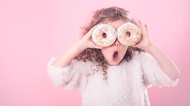 Photo of Portrait of a little surprised girl with donuts