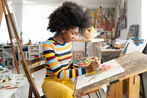Beautiful fine art painter drawing in studio Beautiful fine art painter drawing in studio, holding color palette. Wears casual colorful clothes artists palette photos stock pictures, royalty-free photos & images