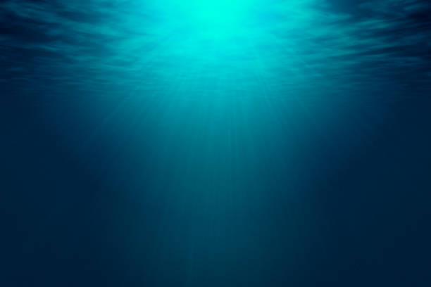 Deep blue sea with rays of sunlight, ocean surface seen from underwater. stock photo