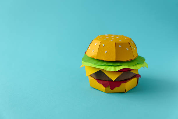 istock Paper cheeseburger with beef, cheese, tomato, lettuce and sauce on a blue background. Copy space. Creative or art food concept 1134487594
