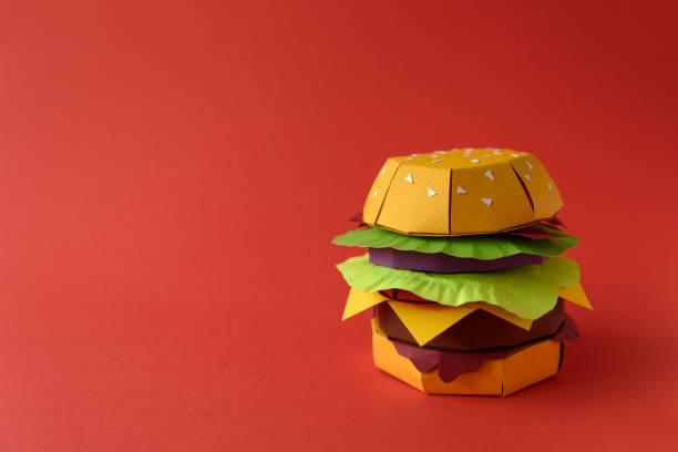 istock Paper cheeseburger with beef, cheese, tomato, lettuce, onion, bacon and sauce on red background. Copy space. Creative or art food concept 1134487598