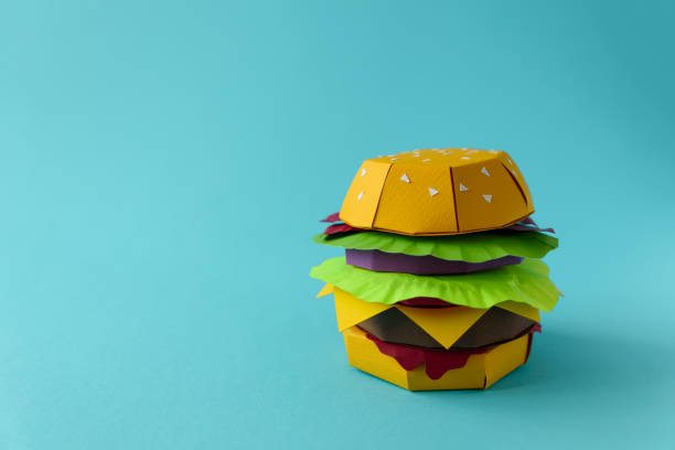 istock Paper cheeseburger with beef, cheese, tomato, lettuce, onion, bacon and sauce on a blue background. Copy space. Creative or art food concept 1134487624