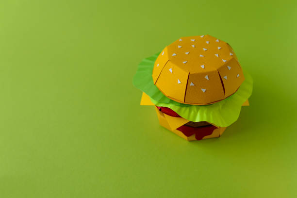 istock Paper cheeseburger with beef, cheese, tomato, lettuce and sauce on a green background. Copy space. Creative or art food concept 1134487656
