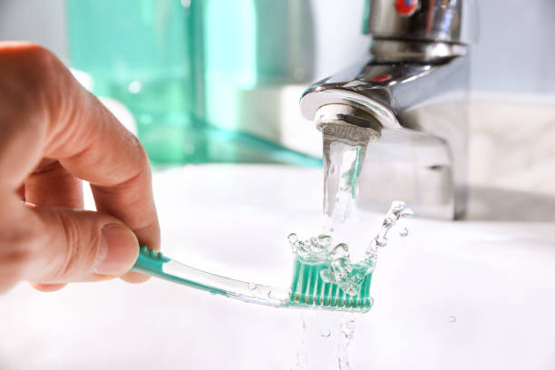 pulizia giornaliera dello spazzolino dopo l'uso nel lavandino del bagno - healthy lifestyle toothbrush caucasian one person foto e immagini stock